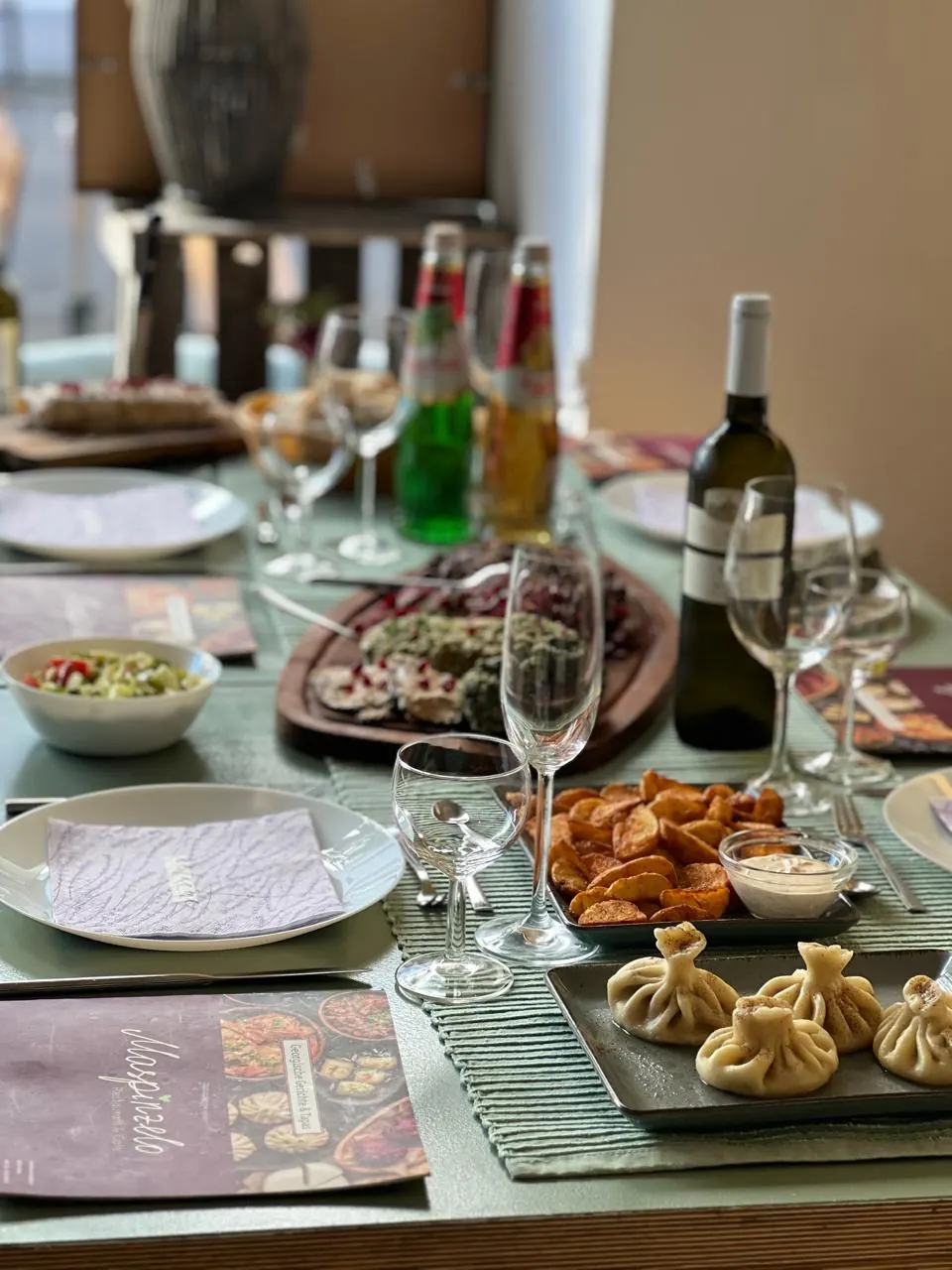 Gedeckter Tisch bei Maspinzelo mit Khinkali, Pkhali, Kartoffelecken und georgischem Weißwein
